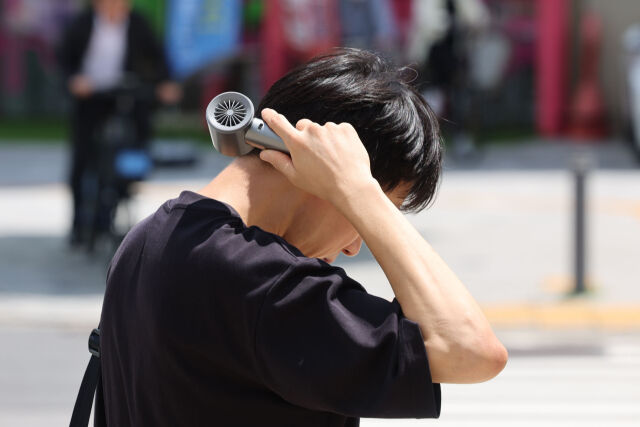서울 송파구 석촌호수 인근에서 한 시민이 목에 선풍기를 대고 있다. /뉴시스