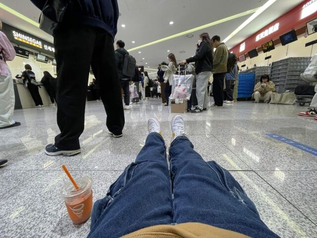 출국 수속에 오랜 시간이 걸리고 다시 면세품 인도장 대기줄이 길어 바닥에 주저앉아 있다. /이지혜 기자
