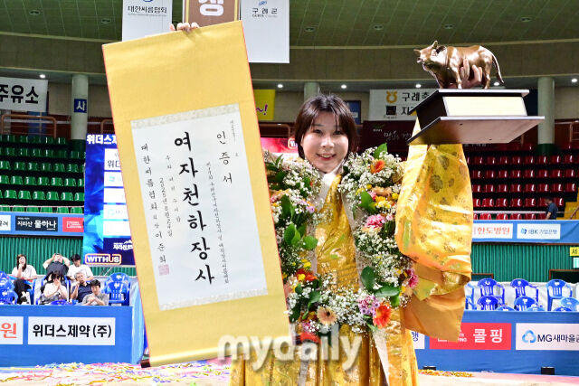 여자천하장사로 등극한 김다영이 트로피를 높이 들며 포즈를 취하고 있다.