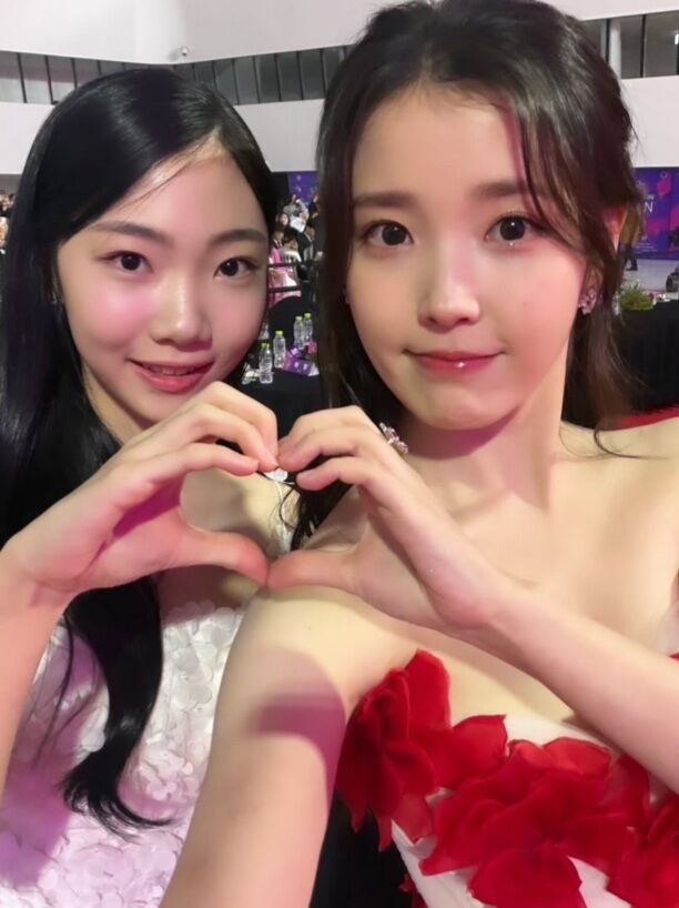 年轻时的金泰妍（艺名Aesoon）遇到IU，用手比划出一个心形：“欧尼，你真漂亮。”