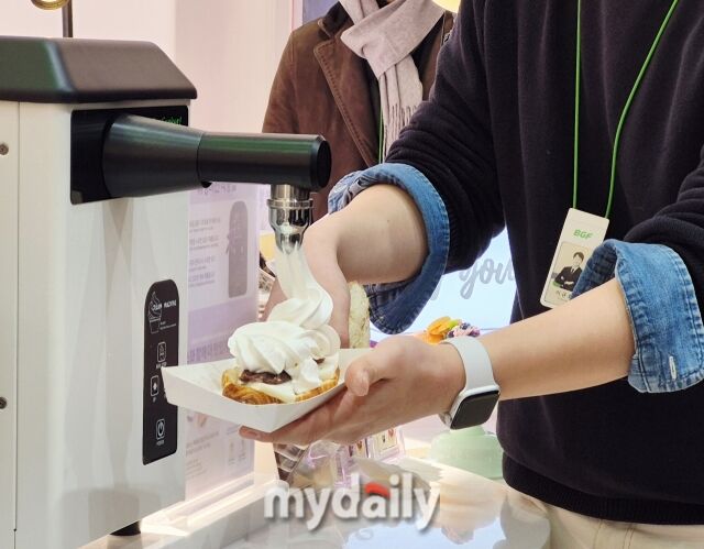 CU 관계자가 직접 구매한 빵에 휘핑크림과 각종 시럽, 토핑을 무료로 추가해 자신만의 메뉴를 만드는 DIY 체험 공간에서 시연을 보이고 있다. /방금숙 기자