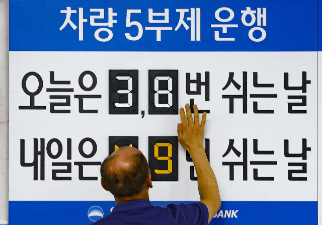 25일 오전 서울 중구 우리은행 본점 주차장에서 한 주차 안내원이 숫자를 조정하고 있다. /뉴시스