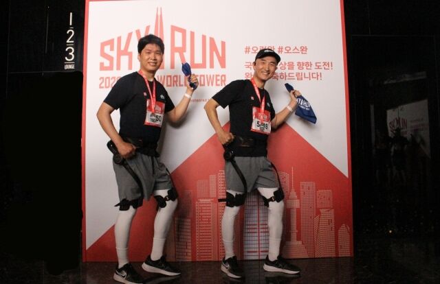 하이퍼쉘 웨어러블 로봇을 착용하고 롯데월드타워 123층에 오른 롯데온 관계자들이 기념 사진을 찍고 있다. /롯데온