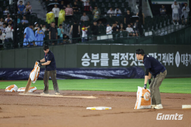 지난 29일 사직구장에서 열린 롯데 자이언츠와 LG 트윈스 경기는 두차례 우천 중단됐고 결국 7회 강우 콜드게임이 선언됐다. 비가 그친 사이 롯데 구단 직원과 관리 요원들이 그라운드를 정비하고 있다./롯데 자이언츠 제공