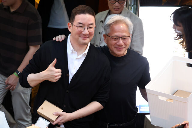 구광모 LG그룹 회장(왼쪽)과 젠슨 황 엔비디아 최고경영자(CEO)가 지난 6월 5일 서울 마포구 홍대 인근의 한 고깃집에서 이른바 '삼소(삼겹살·소주) 회동' 도중 시민들에게 간식을 나눠주다 포즈를 취하고 있다. /뉴시스