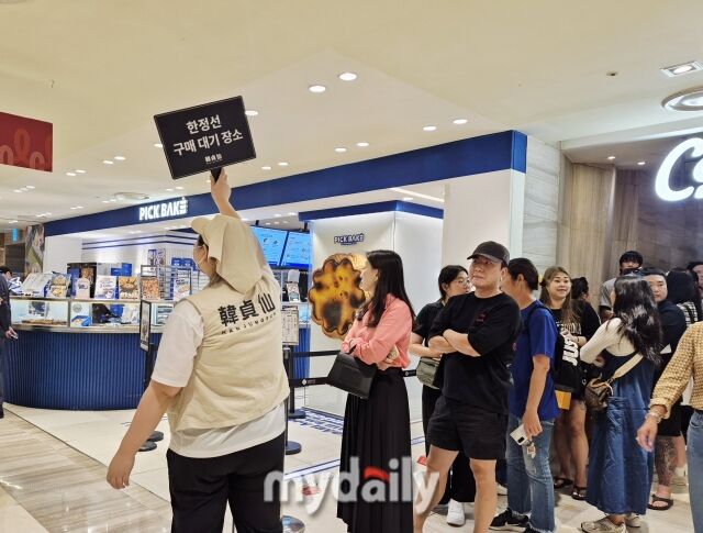한정선 매장 직원이 몰리는 인파로 인한 혼선을 막기 위해 별도로 마련된 대기 장소에서 안내 피켓을 들고 대기 줄을 정돈하고 있다. /방금숙 기자