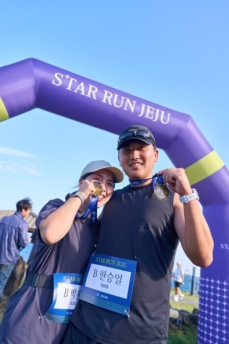 스타런제주’ 참가자들이 결승 아치 앞에서 완주 메달을 들어 보이고 있다. /